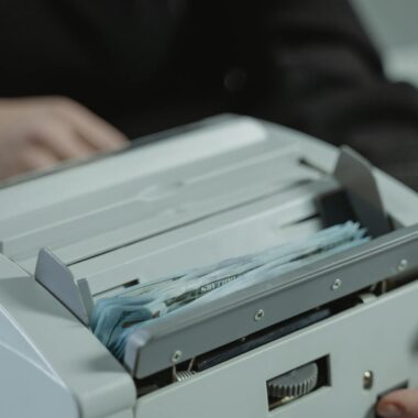 Close-up shot of a money counting machine with bills being processed indoors.