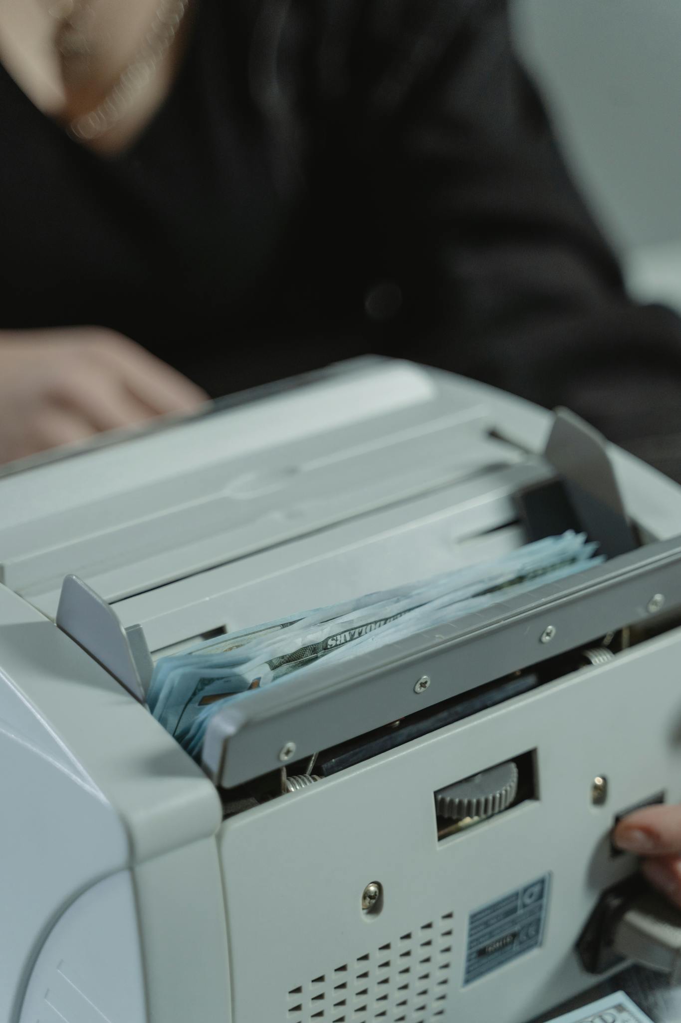 Close-up shot of a money counting machine with bills being processed indoors.